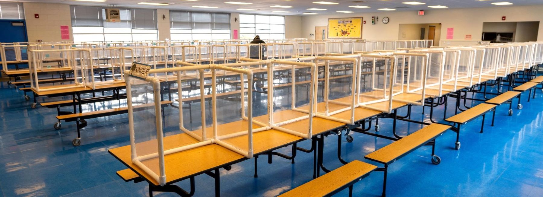 Cafeteria filled with multiple tables and benches arranged for student seating during meals.