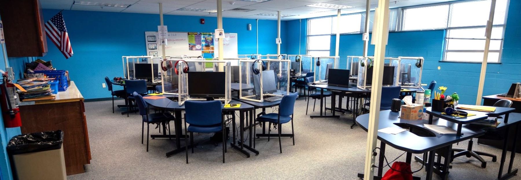 A bright classroom featuring multiple desks and computers, designed for student learning and collaboration.