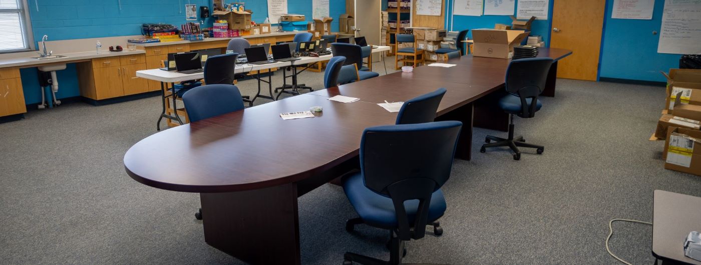 A long conference table surrounded by chairs waiting for meeting members to be productive.