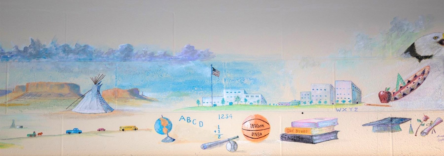 A colorful mural showing a Native American village with traditional homes and symbols of daily activities.