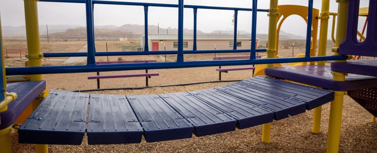  A colorful playground structure stands alone in a vast desert landscape under a clear blue sky.